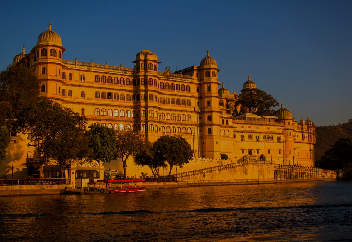 The City Palace of Udaipur rising from Lake Pichola, lit gold by the last of the sun